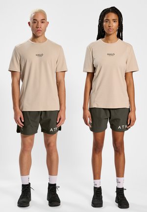 Beige Kurzarm-Sporthemden aus strukturiertem Stoff, kombiniert mit dunkelgrünen Shorts, die den Text "ATW" auf der Vorderseite tragen. Schwarze Schuhe werden gezeigt.