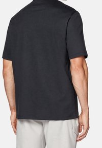 T-shirt en coton noir à manches courtes, avec une coupe décontractée, présentant un col rond et une texture unie, vu de dos.
