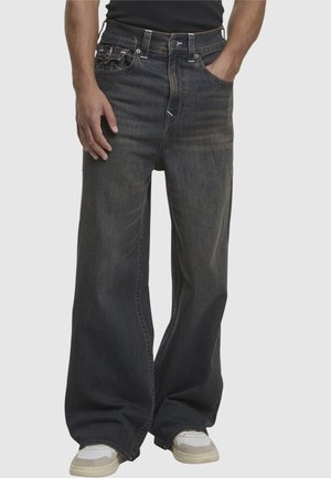 Dunkelblaue weite Jeans mit einer ausgewaschenen Textur, Fünf-Taschen-Design, kontrastierenden Nähten und einem Knopfverschluss an der Taille.