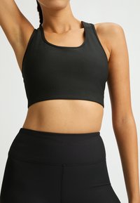 Mustikka raidallinen urheil bra, jossa on neliön muotoinen kaula-aukko ja leveät hihnat. Materiaalilla on sileä pinta ja se on suunniteltu aktiivista pukeutumista varten.