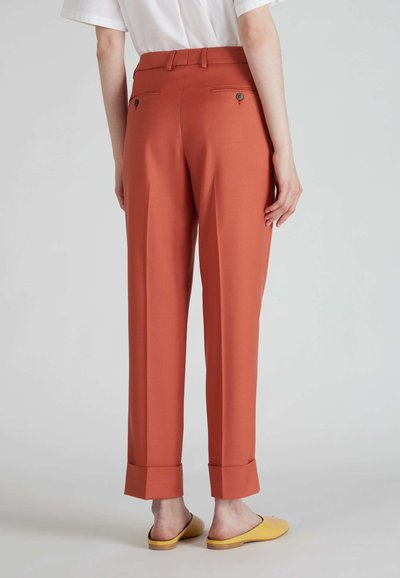 Pantaloni color ruggine con vestibilità dritta, tasche laterali e dettagli a bottone sul retro. Il materiale appare liscio con una leggera lucentezza. Orli con risvolto visibili.