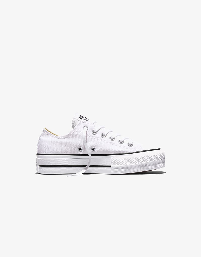 Sneakers bassa in tela bianca con striscia nera sulla suola, lacci bianchi, occhielli in metallo e punta in gomma strutturata, vista laterale su sfondo bianco.