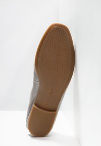 Semelle d'une chaussure Gabor en daim gris montrant une semelle extérieure en caoutchouc marron texturée avec une taille 4½ et les marquages "Fabriqué au Portugal".