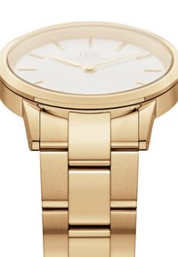 Reloj de acero inoxidable dorado con un bisel pulido, esfera blanca minimalista y marcadores y manecillas de hora dorados. Presenta un diseño de pulsera con eslabones.