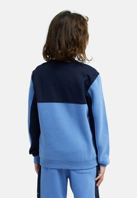 Sweat-shirt bloc de couleur bleu avec partie supérieure bleu marine et partie inférieure bleu clair. Tissu doux, poignets et ourlet côtelés, avec une coupe décontractée.