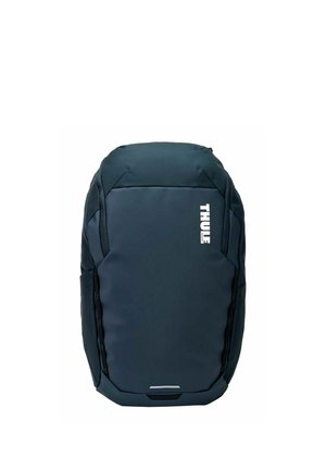 Sac à dos Thule bleu foncé au design élégant et profilé avec un logo blanc vertical sur le devant, comprenant des sections rembourrées et des poches latérales.
