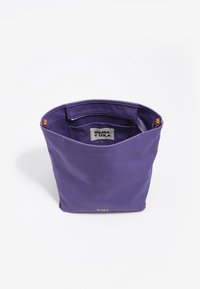 Fioletowa torba na ramię z nylonu o zorganizowanej konstrukcji, z charakterystycznym srebrnym logo i beżowymi akcentami. Wewnątrz znajduje się kieszeń na zamek.