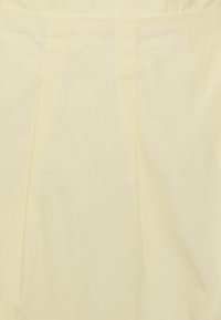 Tecido amarelo-claro com uma textura suave e um brilho sutil, apresentando pregas verticais para adicionar dimensão.