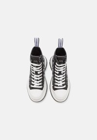 Sneakers alte con un design bianco e nero, caratterizzati da un motivo grafico, lacci bianchi piatti e una suola spessa bianca con un accento nero.