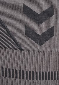 Grå texturerad tyg med horisontell ribbstruktur och kontrasterande svarta chevron- och randmönster som framhäver en sportig design.