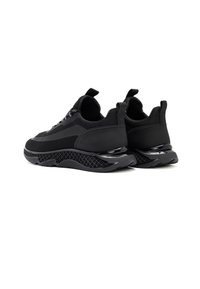 Czarne sportowe sneakersy posiadają połączenie teksturowanej siateczki i gładkich materiałów, z masywną podeszwą i pętelkami na pięcie dla łatwego zakładania.