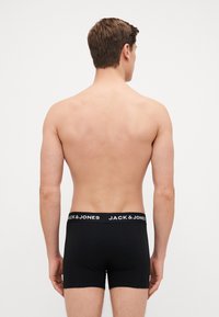 Schwarze Boxer-Briefs mit einem weißen, gebrandeten Bündchen, aus weichem Stoff gefertigt, die eine enganliegende Passform und ein minimalistisches Design zeigen.