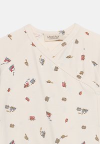 Μαλακό βρεφικό φορμάκι κρέμα με πολύχρωμα μικρά τρένα και αυτοκίνητα τυπωμένα, και σταυρωτό ντεκολτέ με κουμπιά τσίμπημα.