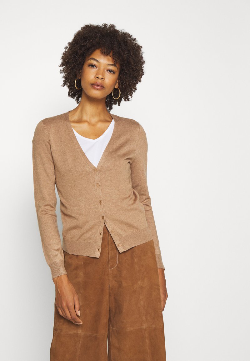 Cardigan marron avec un décolleté en V, des manches longues et six boutons sur le devant. Associé à un pantalon large en daim marron. Texture lisse.