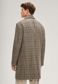 Brauner und beiger Hahnentrittmantel mit langer Silhouette, Reverskragen und glatter Textur, mit dezenten blauen Akzenten.