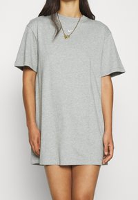 Szary t-shirt krótki rękaw wykonany z materiału bawełnianego. Posiada okrągły dekolt i małe białe logo Nike na piersi. Czysty design.