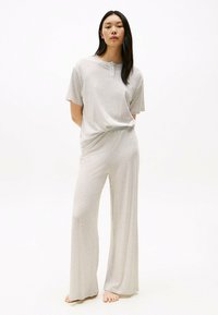 Completo loungewear grigio chiaro composto da una maglietta henley a maniche corte e pantaloni a gamba larga, realizzato in morbido tessuto testurizzato.