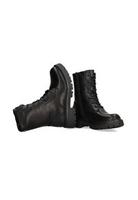 Botas de combate de cuero negro con tobillo alto, cordones en la parte delantera, suela de goma texturizada y tacón plano. Presenta costuras y un zip lateral.