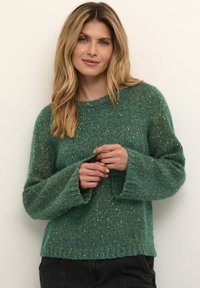 Grön stickad tröja med en texturerad finish, med rund halsringning och trumpetärmar, gjord av ett mjukt, tjockt garn med prickar.