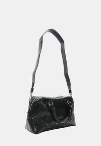 Borsa a mano in pelle nera con doppi manici e una tracolla removibile. Presenta borchie lungo il bordo e una chiusura con zip sulla parte superiore. Design compatto.