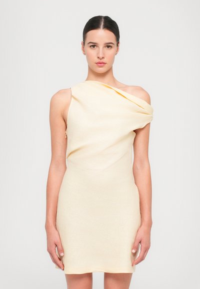 Abito giallo asimmetrico in tessuto morbido e drappeggiato, con spallina unica e silhouette aderente, caratterizzato da una decorazione minima.