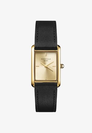 Reloj rectangular de tono dorado con una esfera metálica dorada y correa de cuero negro, que cuenta con marcadores de horas simples y una correa texturizada.