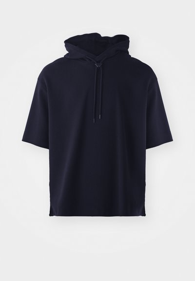 Mornarsko modra kratka majica s kapuco, izdelana iz mehkega blaga, z sprednjim zapiranjem na vrvico in sproščenim krojem. Brez vzorcev ali dodatkov.