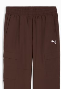 Pantalon cargo marron en tissu léger, doté d'une ceinture élastique, de poches latérales et d'un logo blanc sur la cuisse gauche.