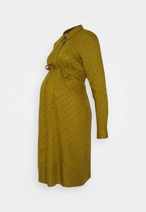 Robe de maternité à manches longues couleur jaune moutarde avec petit motif losange noir et blanc, boutons sur le devant et ceinture à nouer à la taille.