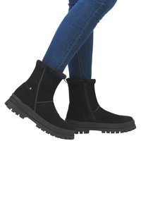 Svarta mocka ankelstövlar med faux pälskant, sidodragkedja och strukturerad gummisula. Stövlarna har rund tå och gedigen design.