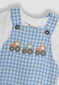 Blauwe en witte geblokte tuinbroek met een wit T-shirt eronder. Bevat geborduurde traktoren in oranje, groen en grijs. Inclusief knoopdetail.