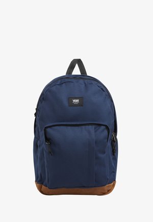 Zaino in tessuto blu navy con fondo in pelle marrone, tasca frontale con zip, forma arrotondata e patch logo nero al centro.