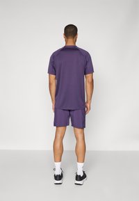Lila träningsskjorta och shorts-set, med korta ärmar och rund hals. Tillverkad av lätt material med en slät textur.
