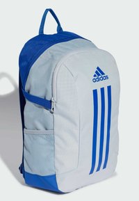 Mochila gris claro con acentos azules, que presenta tres franjas azules, un bolsillo de malla lateral y un asa en la parte superior para llevarla.