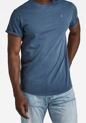 Modré bavlněné tričko s ohrnutými rukávy, kulatým výstřihem a malým logem na hrudi, kombinované s lehkými džínami z denimu.