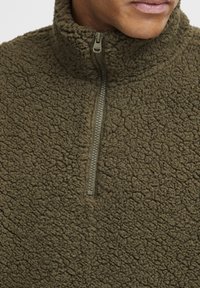 Olive green fleece quarter-zip pullover with a textured exterior and a smooth zipper. Features a high collar and soft, warm fabric.