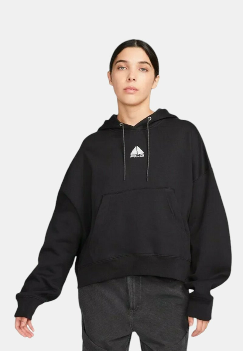 Svart oversized hoodie tillverkad av ett mjukt material, med en framstående känguruficka och en liten logotyp på bröstet. Justerbar dragsko i huvan.