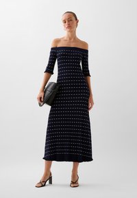 Tummansininen off-the-shoulder ribbed-mekko, jossa on valkoisia vaakaraitoja. Mekossa on kolme neljänneksen hihat ja levenevä helma.