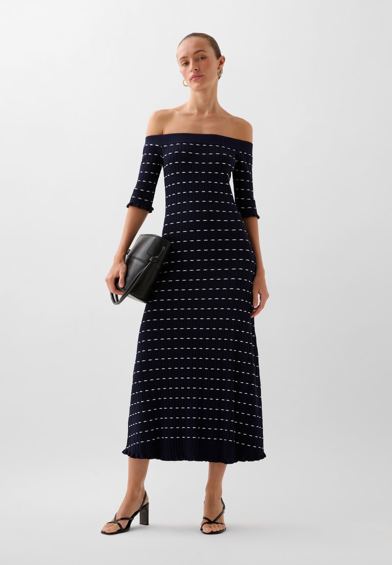 Tummansininen off-the-shoulder ribbed-mekko, jossa on valkoisia vaakaraitoja. Mekossa on kolme neljänneksen hihat ja levenevä helma.