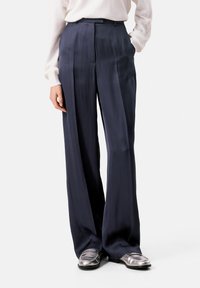 Helleweidige Navy-Hosen aus glattem Stoff mit subtiler Schimmer, ausgestattet mit hoher Taille, scharfen Falten und passgenauer Passform.