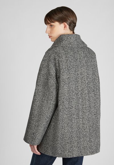 Cappotto grigio a spina di pesce con colletto alto, vestibilità ampia e maniche lunghe. Il tessuto ha una finitura testurizzata e un aspetto morbido.