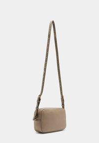Beige læder crossover taske med en rektangulær form, justerbar strop med nitter og hardware i guldtonet. Glat tekstur.