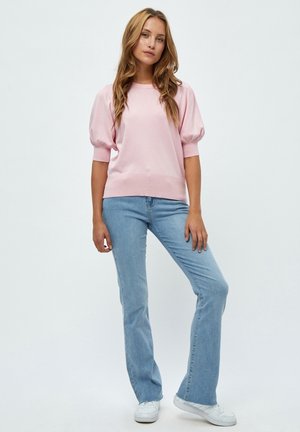 Lichtroze gebreide trui met puffed korte mouwen, gecombineerd met blauwe flare jeans en witte sneakers. Glad textuur en casual ontwerp.