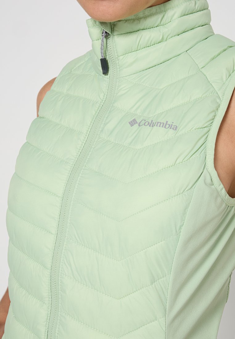 Gilet sans manches vert clair avec un col montant, présentant une texture matelassée, un zip de fermeture et le logo Columbia sur la poitrine.