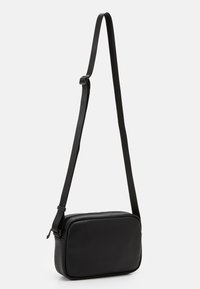 Borsa a tracolla nera con finitura in pelle texturizzata, forma rettangolare e tracolla regolabile. Presenta una chiusura con cerniera e un design minimalista.