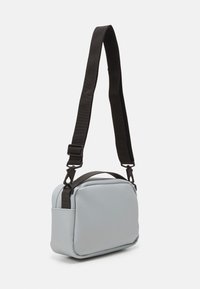 Borsa a tracolla azzurro chiaro realizzata in materiale morbido, con forma rettangolare, tracolla nera regolabile e manico superiore.