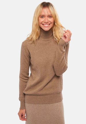 Pull à col roulé marron clair en matériau doux, avec des poignets et un ourlet côtelés, offrant une coupe décontractée et une texture lisse.