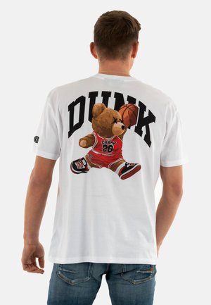 Camiseta de algodón blanca con un gráfico de un oso vestido con ropa de baloncesto roja y zapatos negros, con el texto "DUNK" arriba en negro.