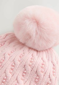 Rosa gestrickte Mütze mit Zopfmuster, verziert mit kleinen Perlen und einem großen Kunstpelz-Pompom oben drauf.