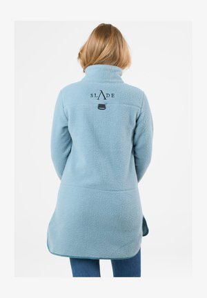 Helle blaue Fleecejacke mit hohem Kragen, auf der Rückseite mit einem schwarzen Logo versehen und mit einem leicht geschwungenen Saum für eine entspannte Passform.